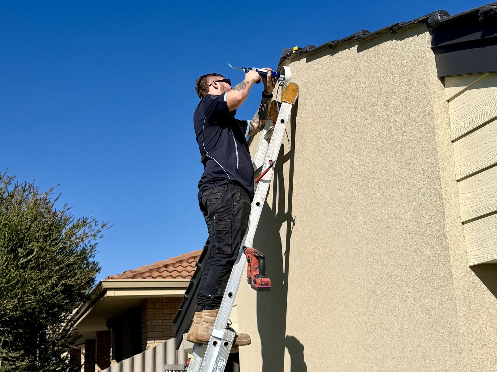 North Side Security technician mounting a CCTV camera under the roofline of a Perth home